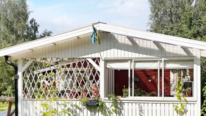 A white wooden structure with a sloped roof, a lattice window, and potted plants around it. - 5 Person Holiday Home in Sodertalje (Sodertalje)