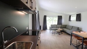 Eine moderne Küche mit Spüle aus Edelstahl und einer Essecke mit Holztisch und Stühlen.
