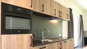 Eine moderne Küche mit Holzschränken, einem Edelstahl-Spülbecken und einem eingebauten Backofen.