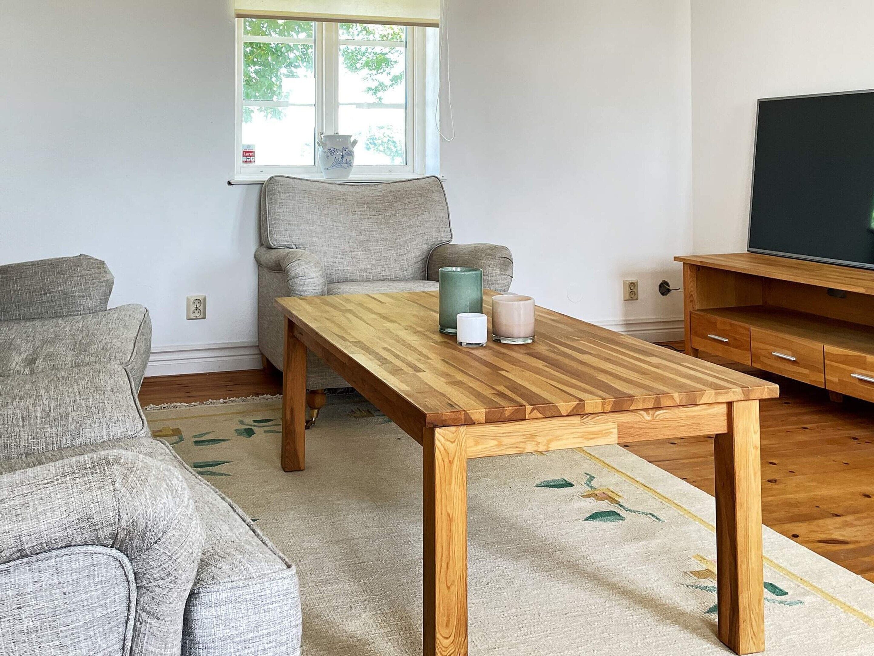 A living room with a wooden coffee table, grey sofa, and a television on a wooden stand.