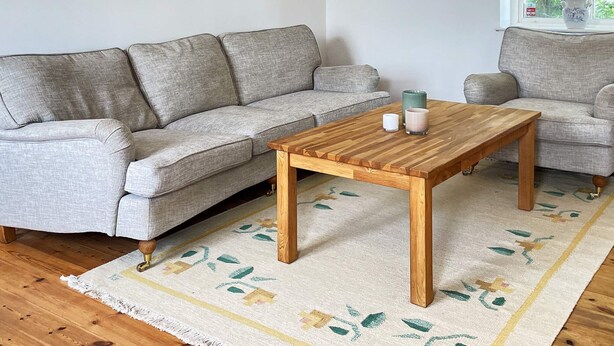 A living room with a grey sofa, a wooden coffee table, and a patterned rug. - 8 Person Holiday Home in Skivarp (Skivarp)