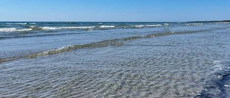 A beach with clear water and waves.