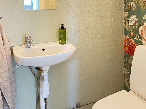 A bathroom with a white sink, a green soap dispenser, and a floral wallpaper. - 8 Person Holiday Home in Skivarp (Skivarp)