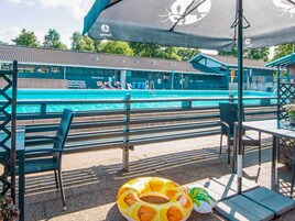 Zona junto a la piscina con sillas de descanso y puesto de salvavidas.