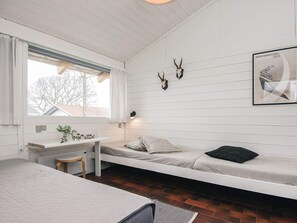 A room with a bed, a desk, and a chair. There is a window with curtains, a plant on the desk, and a picture on the wall. - 5 Person Holiday Home in Aabenraa (Aabenraa)