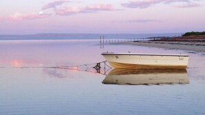 A boat anchored on a calm body of water with a pier in the background.