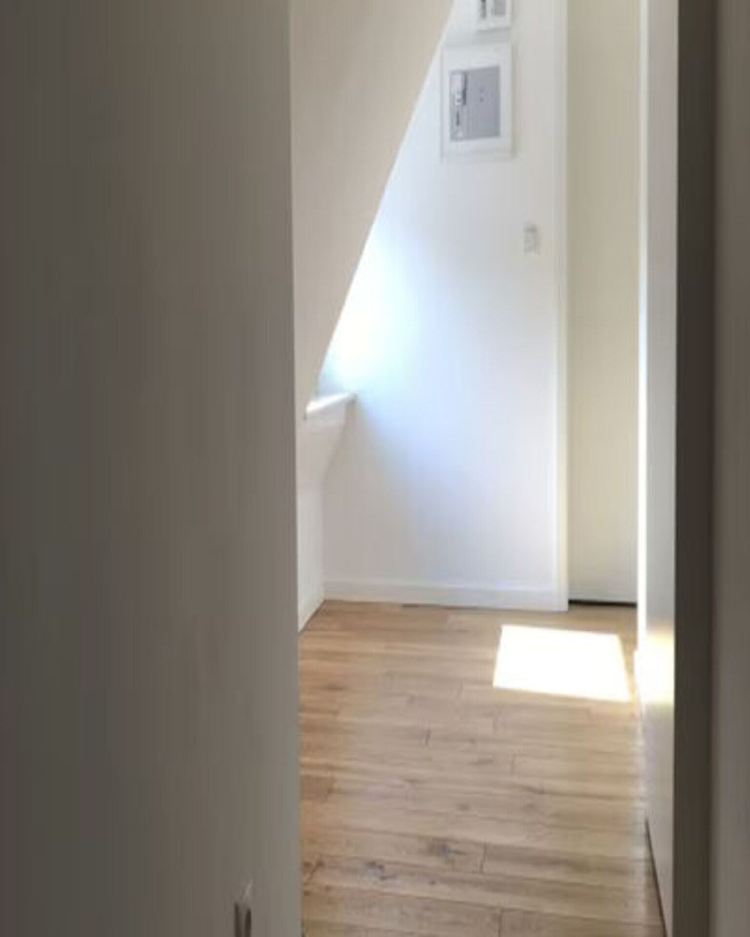Ein schmaler Korridor mit Holzdielen und schräg verlaufender Decke.