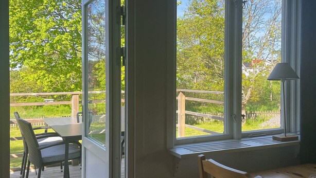 Een kamer met een groot raam met uitzicht op een terras en groen.