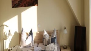 A bedroom with a bed, pillows, bedside lamps, and a painting on the wall. - Borkum Ideal 71 A Comfortable Holiday Residence (Borkum)
