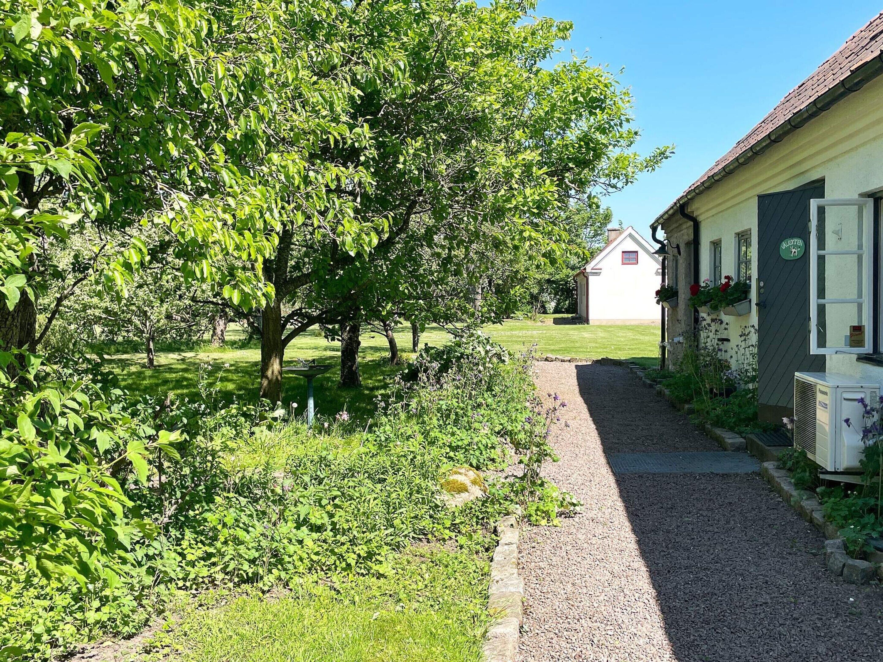 A pathway leading to a building with a white exterior and a green sign.