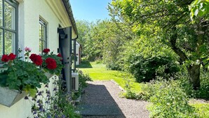 A pathway leading to a building with a window displaying red flowers. - 6 Person Holiday Home in Kattarp (Kattarp)