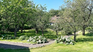 A garden with various trees and a building in the background. - 6 Person Holiday Home in Kattarp (Kattarp)