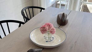 A dining table with a vase of pink flowers, a ceramic bird, and a decorative bowl. - 5 Star Holiday Home in Bohus Malmon (Bohus-Malmon)