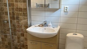 A bathroom with a white sink, a mirror, and a shower area with brown tiles. - 5 Star Holiday Home in Bohus Malmon (Bohus-Malmon)