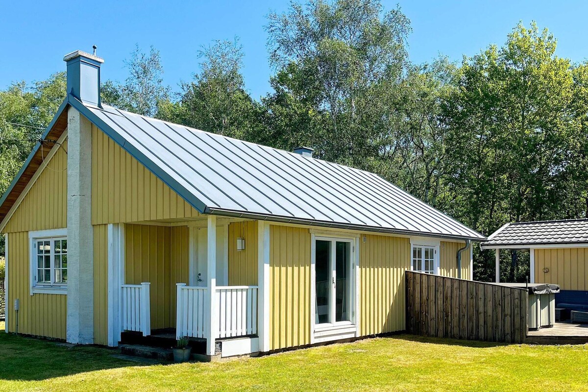 A single-story yellow building with a gabled roof, a front porch, and a fenced yard.