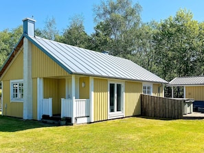A single-story yellow building with a gabled roof, a front porch, and a fenced yard. - 4 Star Holiday Home in Skummeslovsstrand (Skummesloevsstrand)