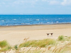 A beach with a sandy shore and a bench. - 4 Star Holiday Home in Skummeslovsstrand (Skummesloevsstrand)