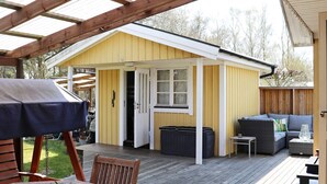 A covered patio area with a wooden deck, a small shed with a door, and outdoor furniture including a table and chairs. - 4 Star Holiday Home in Skummeslovsstrand (Skummesloevsstrand)