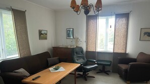 A furnished living room with a sofa, two armchairs, a wooden table, a desk with a lamp, and a chandelier. - 6 Person Holiday Home in Tingsryd (Tingsryd)