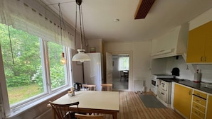 A kitchen with wooden flooring, a dining area with a table and chairs, and a view of greenery outside. - 6 Person Holiday Home in Tingsryd (Tingsryd)