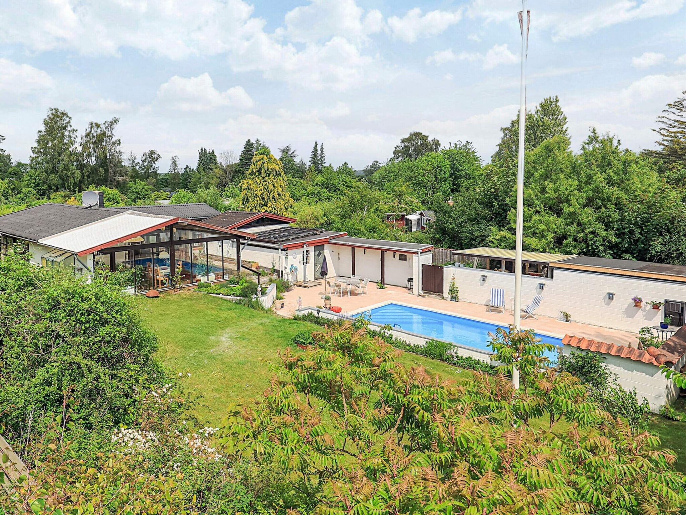 A residential property with a swimming pool, a covered patio, and a large garden area.