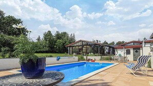 A swimming pool with a covered patio area, a table with a potted plant, and a chair. - 5 Person Holiday Home in Frederiksvaerk (Frederiksvaerk)