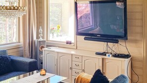 Een woonkamer met een televisie, een glazen salontafel, een bank en een kast.