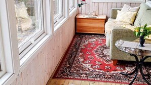 Een knus vertrek met een houten bankje, een sofa en een kleine tafel met een vaas.