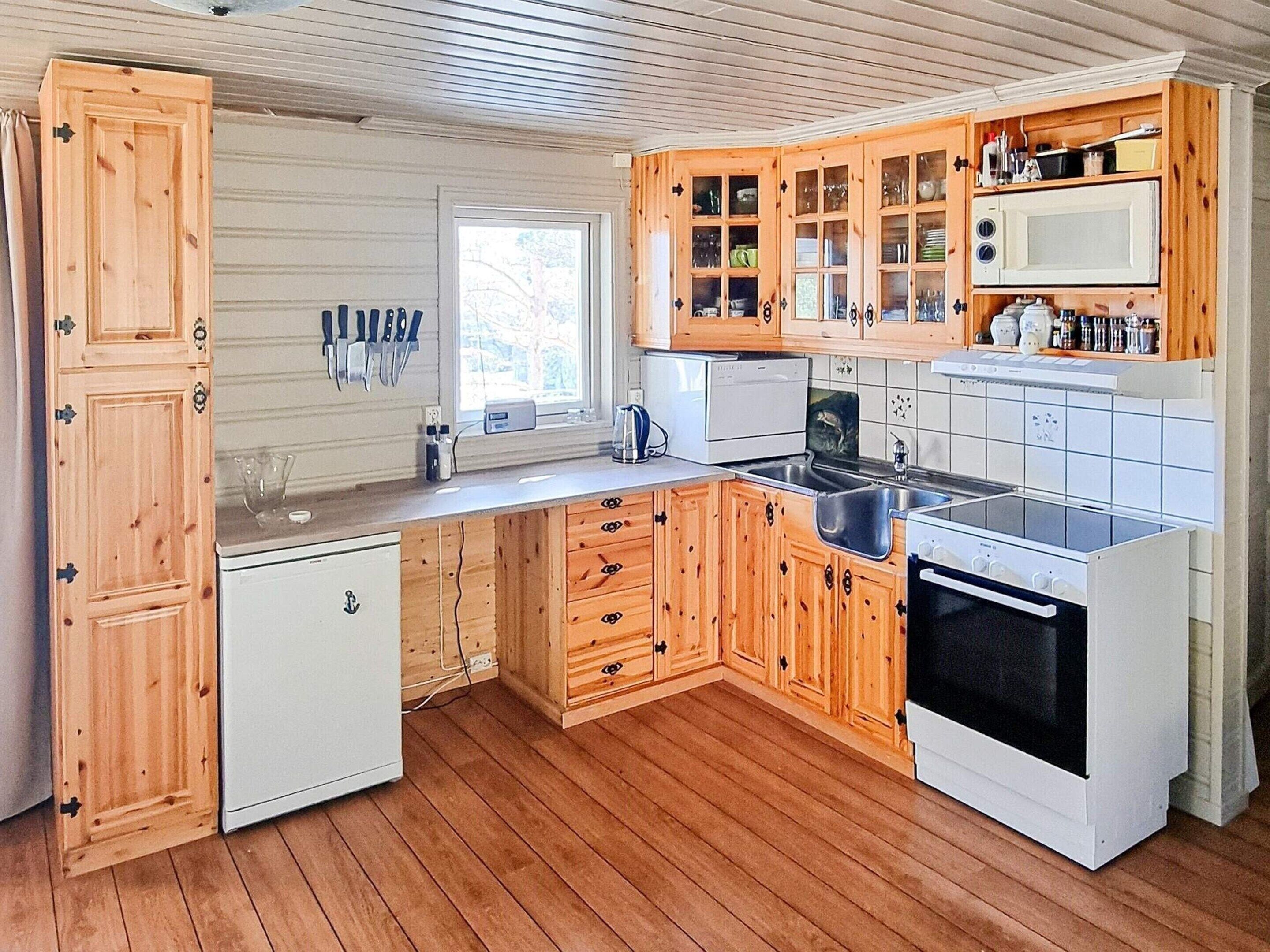 Eine kleine Küche mit Holzausstattung, einer eingebauten Mikrowelle und einem Kühlschrank.
