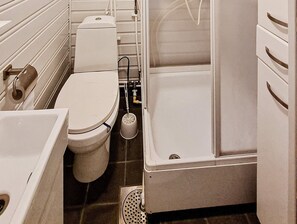 Bathroom features a white toilet, sink, and bathtub, with a tiled floor and small window.