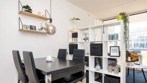 Een moderne kantoorruimte met een donker houten tafel, zwarte stoelen en een wit bergingsrek met diverse spullen.