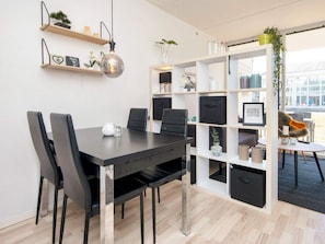 Un espace de bureau moderne avec une table en bois foncé, des chaises noires et une étagère blanche contenant divers objets.