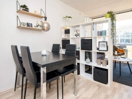 Un espacio de oficina moderno con una mesa de madera oscura, sillas negras y una estantería blanca con diversos objetos.