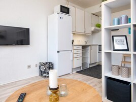 Una cocina compacta con armarios blancos, un microondas y un horno pequeño.