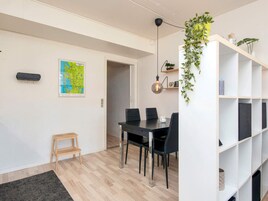 Un espacio de estar moderno con comedor, un mapa en la pared, un taburete de madera y una estantería blanca con plantas.