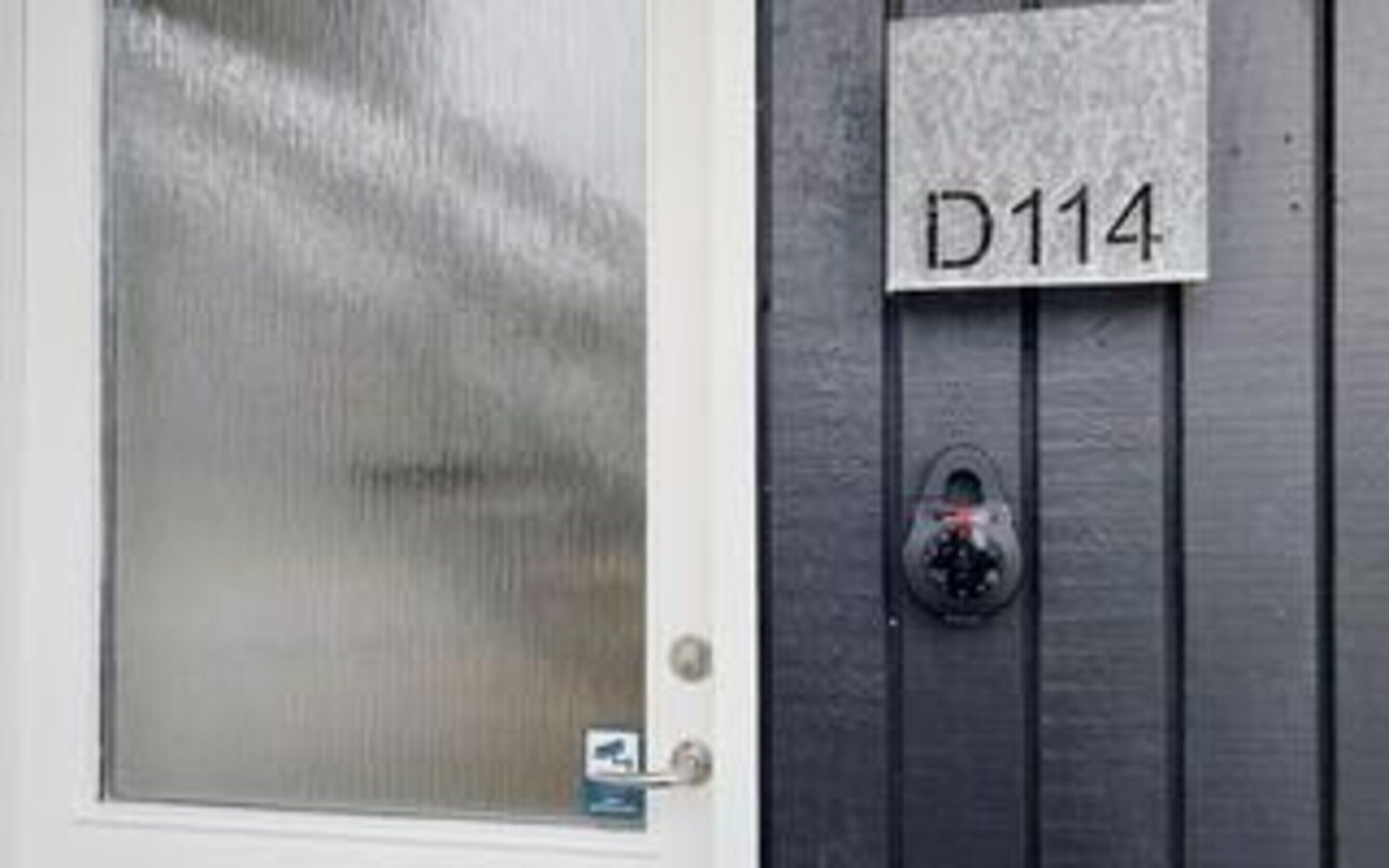 A door with frosted glass and a keypad lock. A sign with 'D114' is mounted on the wall.