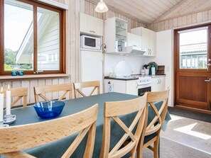 Une cuisine chaleureuse avec des meubles en bois, un four à micro-ondes, une cuisinière et une table à manger avec des chaises.