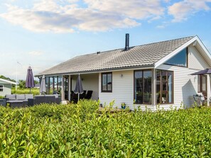 Une maison de plain-pied avec un porche couvert, de grandes fenêtres et une cheminée.