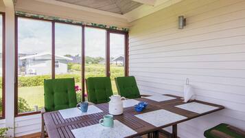 Un patio abrité avec une table, des chaises et une vue sur les environs.