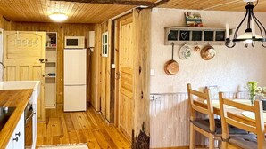 Un intérieur en bois comprenant un coin cuisine, une table à manger avec des chaises et un luminaire suspendu.