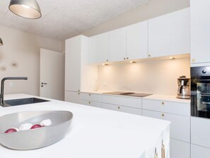 A modern kitchen with white cabinetry, a stainless steel sink, and a built-in oven. - 5 Star Holiday Home in Vestervig (Vestervig)
