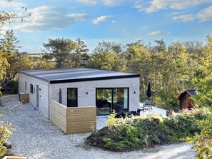 A modern, single-story house with a flat roof, large glass windows, and a wooden deck. - 5 Star Holiday Home in Vestervig (Vestervig)