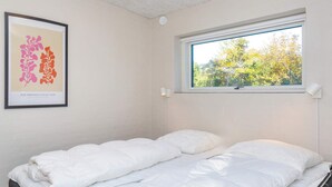 A bedroom with a bed, a window with a view of trees, and a framed artwork on the wall. - 5 Star Holiday Home in Vestervig (Vestervig)