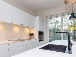 A modern kitchen with white cabinetry, a black sink, and a coffee machine. - 5 Star Holiday Home in Vestervig (Vestervig)