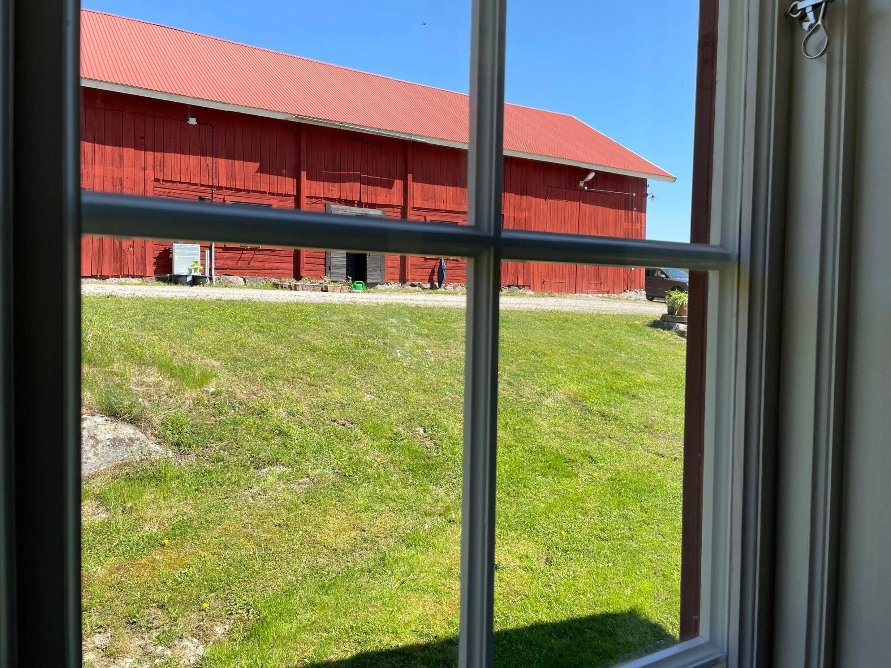 A red barn with a clear view through a window.