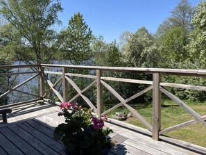 A wooden deck with a railing overlooking a body of water, surrounded by trees.