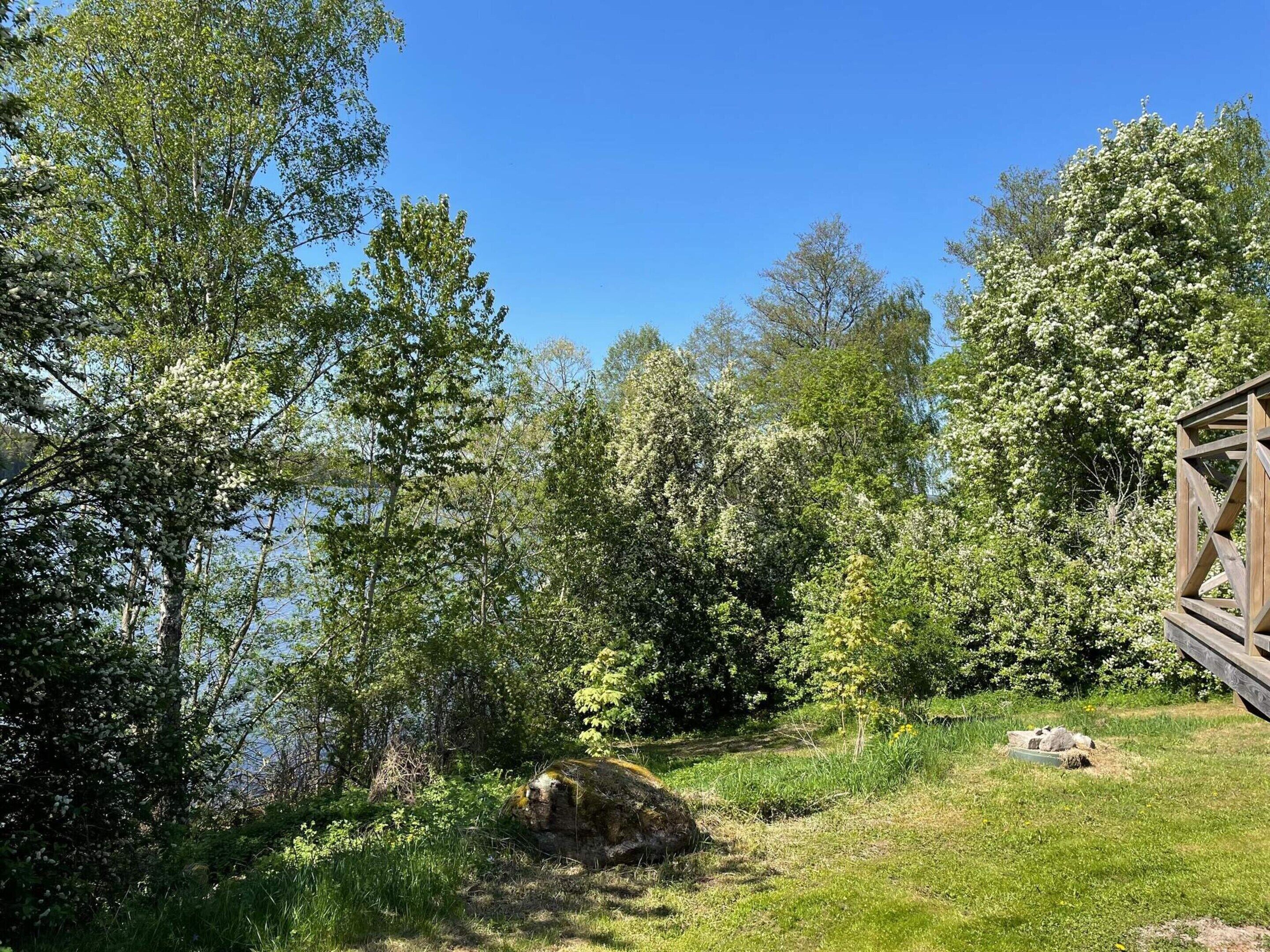 A natural landscape with a wooden cabin and a lake.