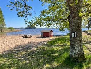A lakeside picnic area with a red shed, a picnic table, and a trail leading to the water. - 4 Star Holiday Home in Sparreholm (Sparreholm)