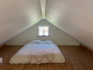 A room with a sloped ceiling, a window with a view, and a bed with a patterned bedspread. - 4 Star Holiday Home in Sparreholm (Sparreholm)