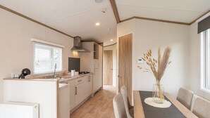 A modern kitchen with a central island, a dining area with a table and chairs, and a view of the adjacent room. - Chalet in De Haan Near Sandy Beaches (De Haan)